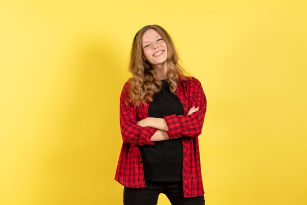 Mulher jovem de frente para a camisa quadriculada vermelha posando com um sorriso no fundo amarelo cor humana modelo mulher emoção