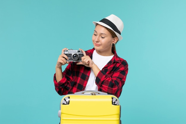 Mulher jovem de frente para a viagem e segurando a câmera no piso azul, viajando no mar, viajando, avião, viagem