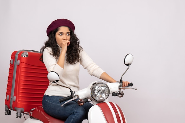 Mulher jovem de frente para bicicleta com sua bolsa no fundo branco.