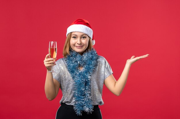 Mulher jovem de frente para comemorar o ano novo na parede vermelha feriado cor natal