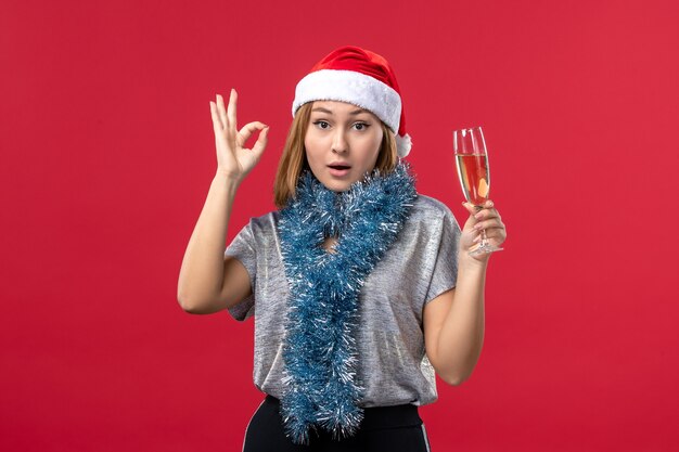 Mulher jovem de frente para comemorar o ano novo na parede vermelha, festa de Natal, feriado