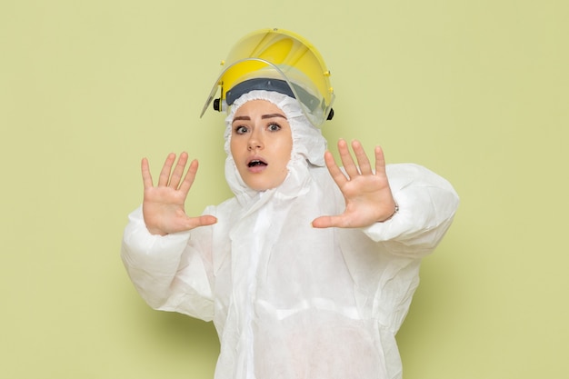 Mulher jovem de frente para o terno especial branco e capacete amarelo posando no trabalho do espaço verde