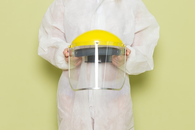 Mulher jovem de frente para o terno especial branco e capacete amarelo segurando-a no espaço verde