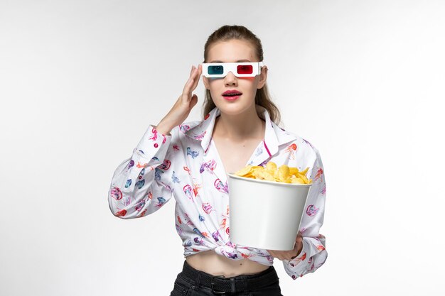 Mulher jovem, de frente, segurando a cesta com batatas fritas em óculos de sol d na superfície branca