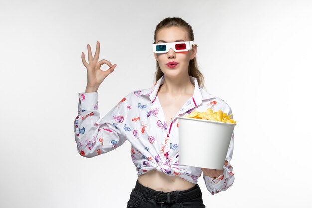 Foto grátis mulher jovem, de frente, segurando a cesta com batatas fritas em óculos de sol d na superfície branca