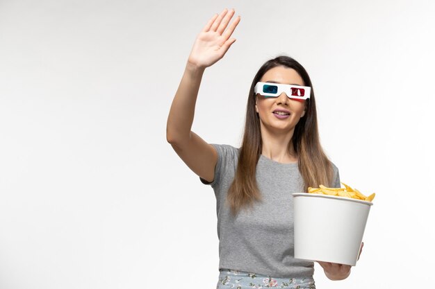 Mulher jovem de frente segurando fichas e assistindo filme com óculos de sol na mesa branca