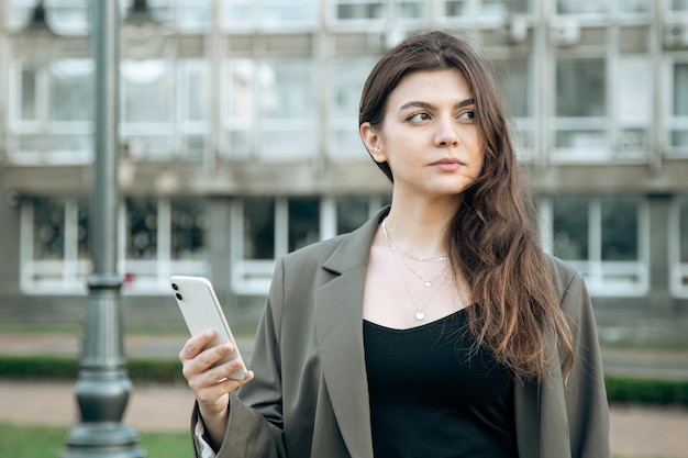 Mulher jovem de negócios com um smartphone em um fundo desfocado da cidade