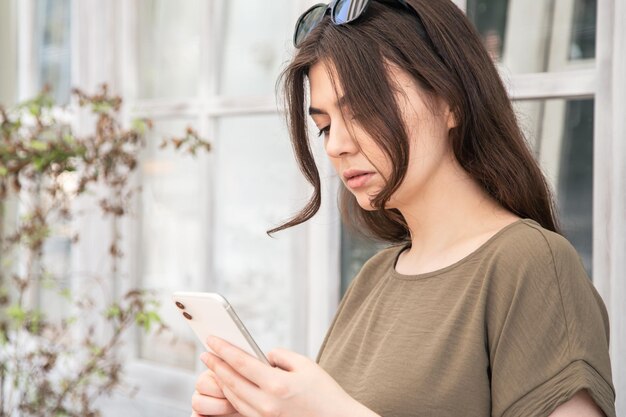 Mulher jovem de negócios com um smartphone nas mãos em um dia quente de verão