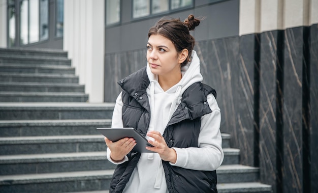 Mulher jovem de negócios com um tablet no fundo do edifício