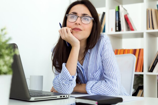 Mulher jovem de negócios que trabalha com laptop no escritório.