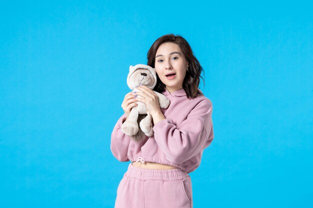 Mulher jovem de pijama rosa com ursinho de brinquedo azul, vista frontal
