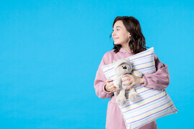 Mulher jovem de pijama rosa conversando com alguém na cama azul festa insônia noite pesadelo descanso sono