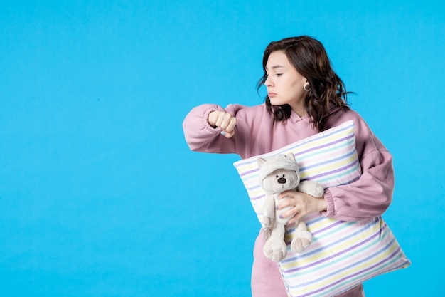 Mulher jovem de pijama rosa verificando as horas na parede azul festa insônia cama noite pesadelo sonho descanso