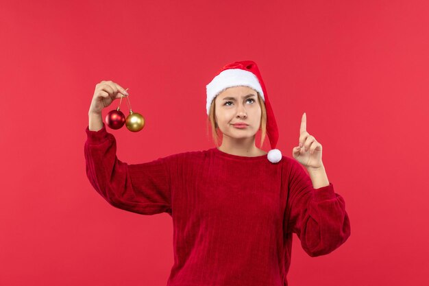 Mulher jovem de vista frontal com brinquedos de bola de natal, feriado natal vermelho