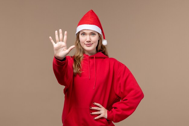 Mulher jovem de vista frontal mostrando número no fundo marrom emoção feriado de natal