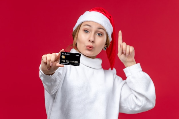 Mulher jovem de vista frontal posando com cartão do banco em fundo vermelho