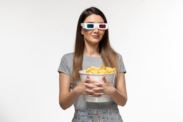 Mulher jovem de vista frontal segurando fichas e assistindo filme em óculos de sol na superfície branca