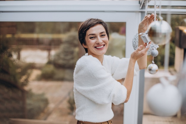 Mulher jovem decorando a casa com brinquedos de natal