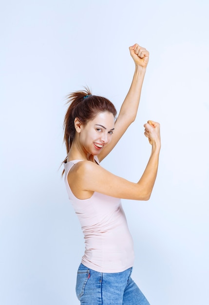 Mulher jovem demonstrando os músculos do braço, vista de perfil