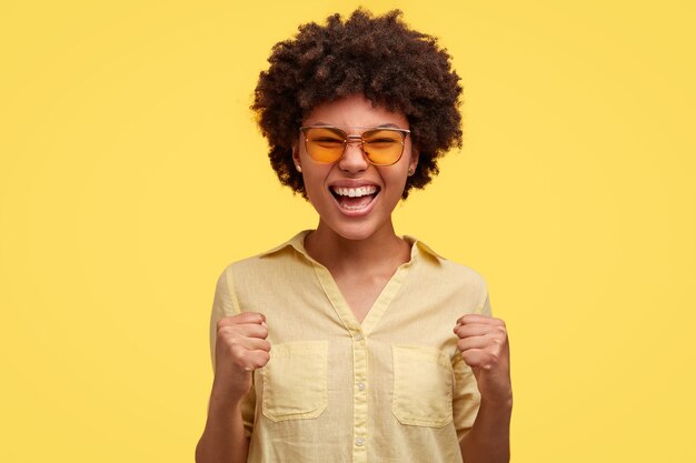 Mulher jovem desesperada com corte de cabelo afro, franze a testa e cerrou os dentes, parece zangada, tem expressão irritada