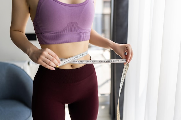 Foto grátis mulher jovem desportiva e medida em torno de seu corpo em casa.