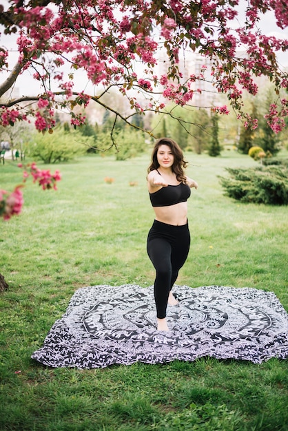 Mulher jovem desportiva exercitando no jardim, olhando para a câmera