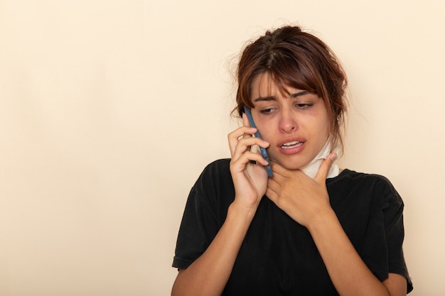 Foto grátis mulher jovem doente de vista frontal se sentindo muito mal e falando ao telefone em uma superfície branca