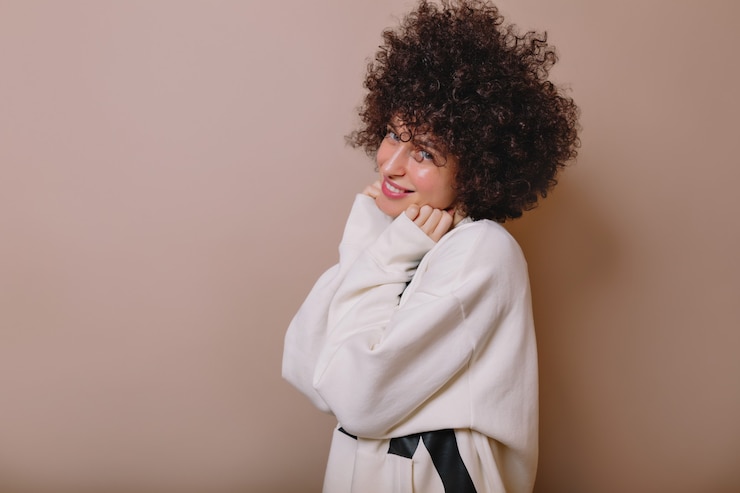 Foto grátis mulher jovem e adorável inspirada rindo em um pulôver fofo posando em bege