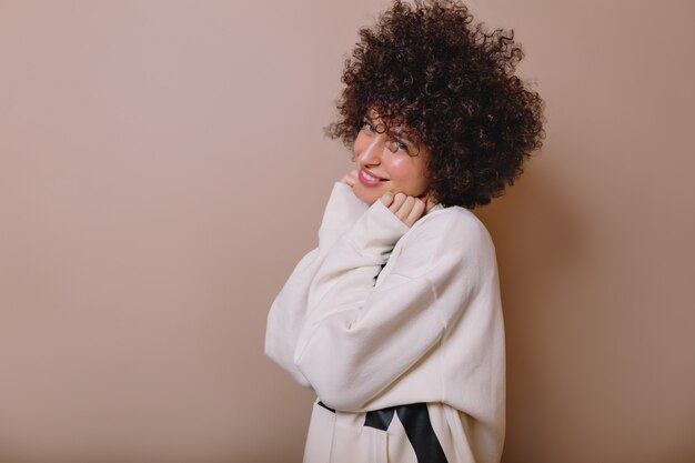 Mulher jovem e adorável inspirada rindo em um pulôver fofo posando em bege
