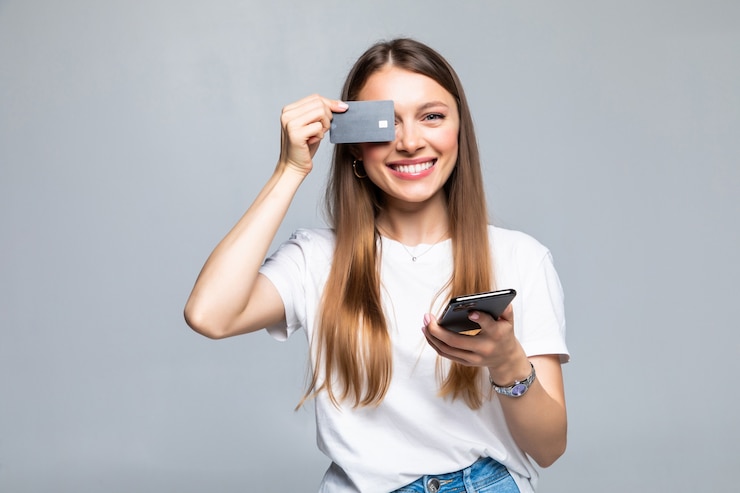 Foto grátis mulher jovem e animada com telefone celular e cartão de crédito