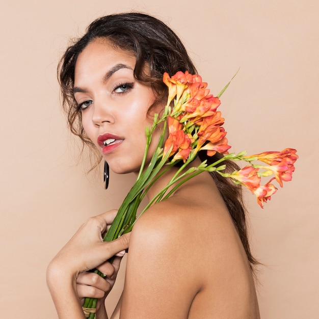 Mulher jovem e atraente com flores por cima do ombro