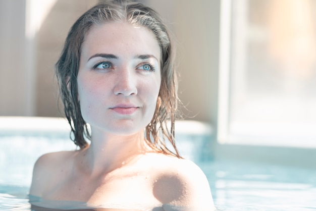 Mulher jovem e atraente com o cabelo molhado na piscina