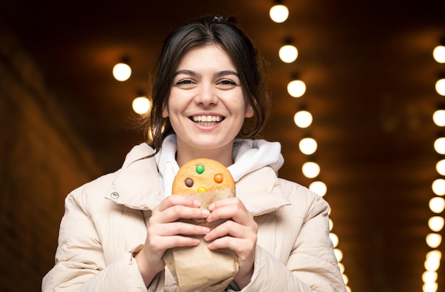 Foto grátis mulher jovem e atraente com pão de gengibre em um fundo desfocado com bokeh