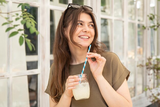 Mulher jovem e atraente com um copo de limonada em um dia quente de verão
