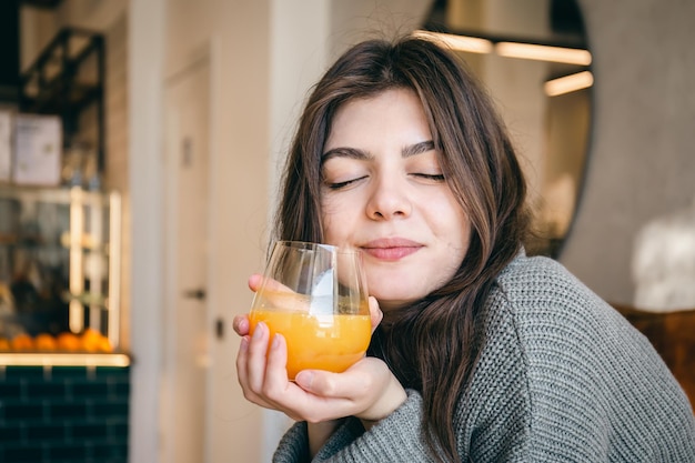Mulher jovem e atraente com um copo de suco de laranja espremido na hora