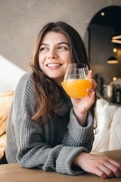 Mulher jovem e atraente com um copo de suco de laranja no interior de um café