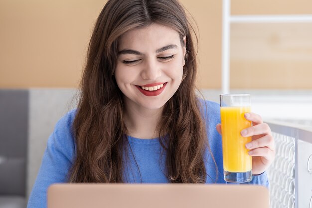 Mulher jovem e atraente com um suéter azul trabalhando em um laptop em um café