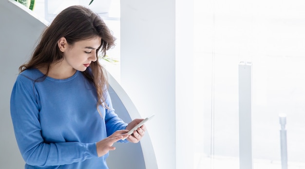 Mulher jovem e atraente com um suéter azul usa o espaço da cópia do telefone