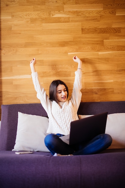 Foto grátis mulher jovem e atraente feliz trabalhar em casa, esticando os braços para relaxar após um dia difícil