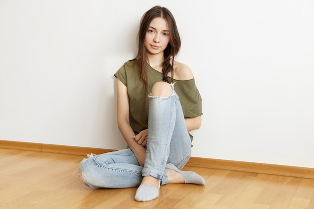 Mulher jovem e atraente morena usando jeans rasgados da moda e top com ombros abertos