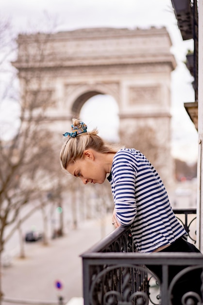 Mulher jovem e atraente na varanda de manhã na cidade de paris. vista do arco triunfal.