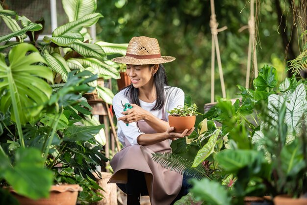 Mulher jovem e atraente trabalhando com plantas decorativas no centro de jardim. supervisor feminino examinando plantas em jardinagem fora na natureza de verão. Lindo jardineiro sorrindo. cuidados com as plantas.