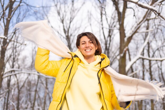 Mulher jovem e bonita alegre em uma floresta de inverno com neve, se divertindo, se alegra no inverno e neve em roupas quentes