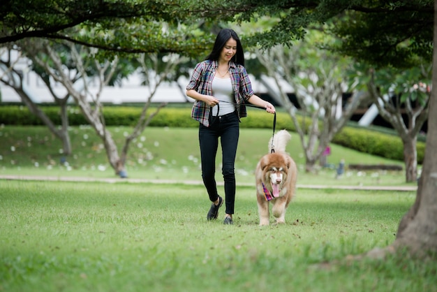 Mulher jovem e bonita brincando com seu cachorro pequeno em um parque ao ar livre. retrato do estilo de vida.