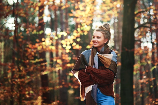 Mulher jovem e bonita caminhando na floresta de outono