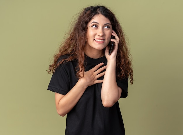 Foto grátis mulher jovem e bonita caucasiana alegre falando no telefone, olhando para o lado, fazendo gesto de agradecimento