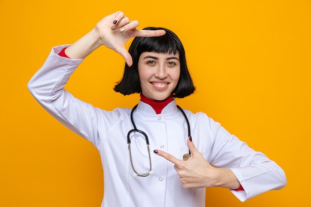 Mulher jovem e bonita caucasiana sorridente com uniforme de médico e estetoscópio gesticulando com as mãos