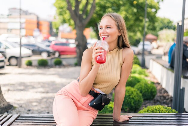 Mulher jovem e bonita com coquetel em um café de rua