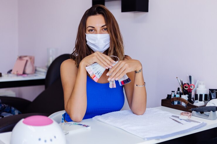 Foto grátis mulher jovem e bonita com máscara médica protetora em salão de beleza de unhas com luz suave natural incrível