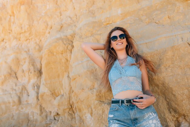 Mulher jovem e bonita com óculos de sol na praia rochosa